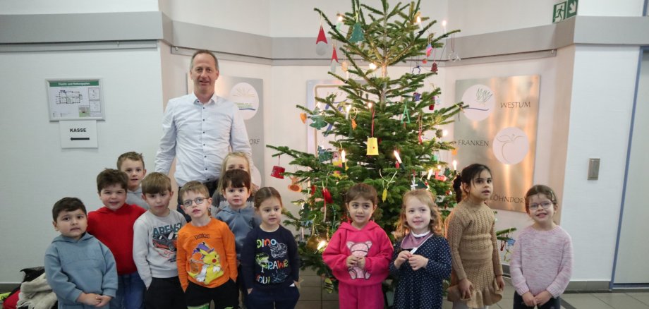 Kita-Kinder schmücken Weihnachtsbaum Das Foto zeig die Kita-Kinder und den Büroleiter vor dem geschmückten Weihnachtsbaum.