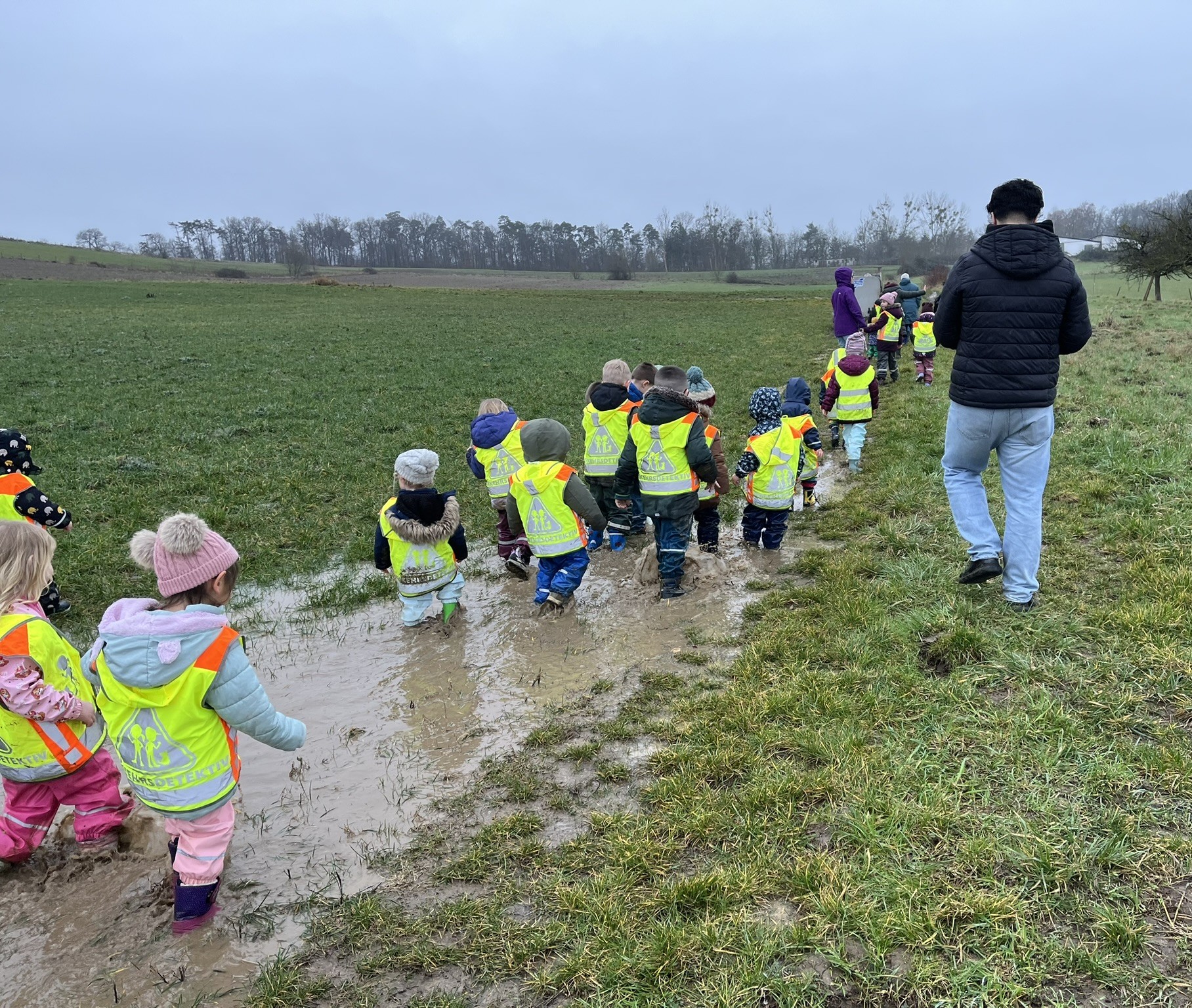 Das Foto zeigt die Kita-Kinder beim Marsch durch die tiefen Pfützen.