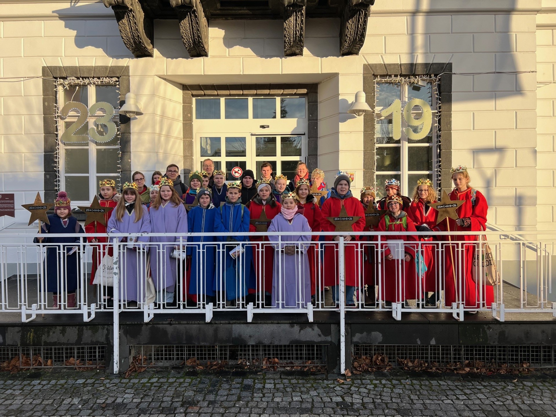Das Foto zeigt Sternsinger vor dem Sinziger Rathaus zusammen mit Bürgermeister Andreas Geron.