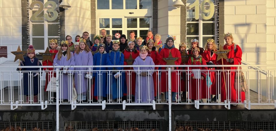 Das Foto zeigt Sternsinger vor dem Sinziger Rathaus zusammen mit Bürgermeister Andreas Geron.