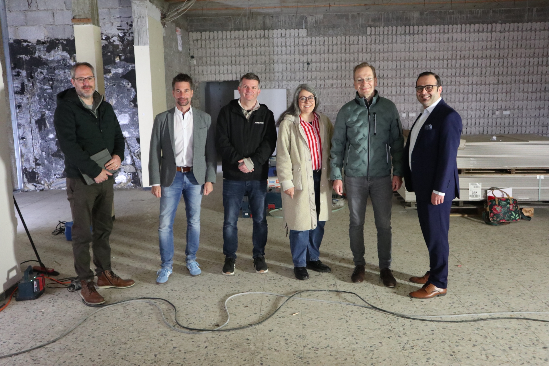 Das Foto zeigt den Bürgermeister sowie Mitarbeiterinnen und Mitarbeiter der Stadt gemeinsam mit Vertretern der VR Bank auf der Baustelle.