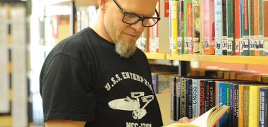 Dieses Bild zeigt einen Mann beim Blättern in Büchern in der Sinziger Stadtbibliothek.