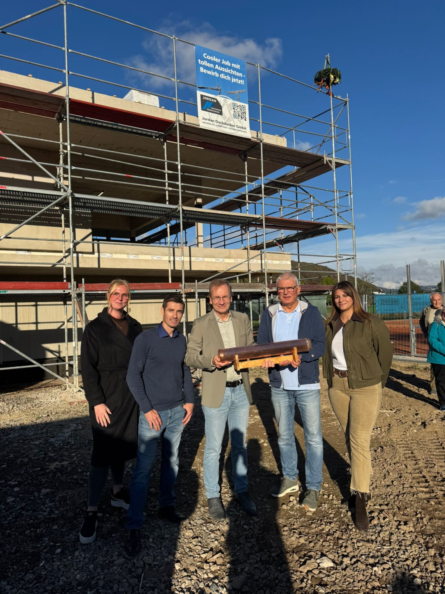 Das Foto zeigt von links nach rechts Nadine Baumann (Projektleitung Gewi), Vitali Jordan (Inhaber Jordan Dachdecker GmbH), Bürgermeister Andreas Geron, Ralf Barnekow(1.Vorsitzender des Tennis Club) und Olga Weins (Architekturbüro Schneiderarchitektur) bei der Übergabe der Zeitkapsel.