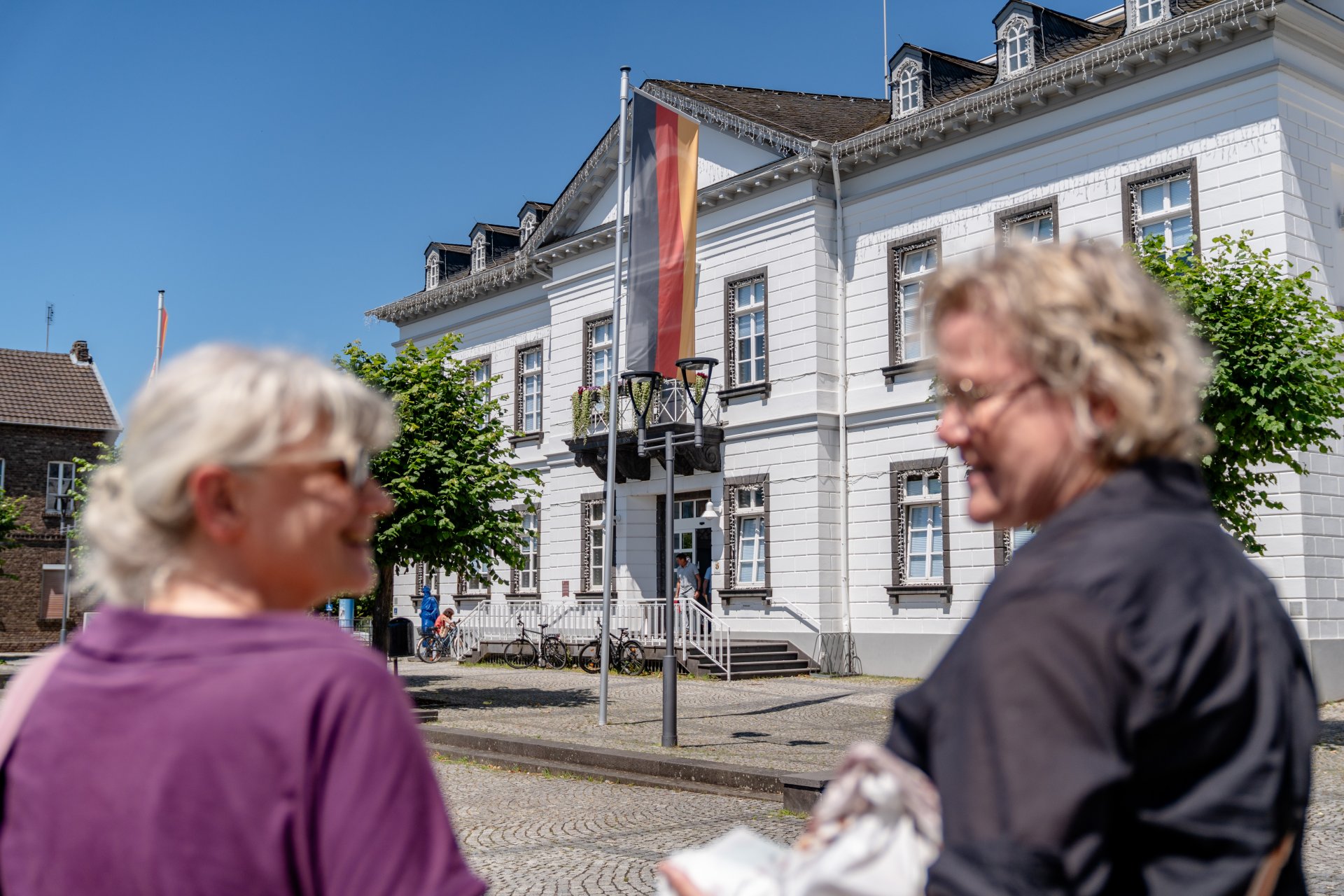 Dieses Foto zeigt 2 Personen, die sich vor dem Rathaus unterhalten.