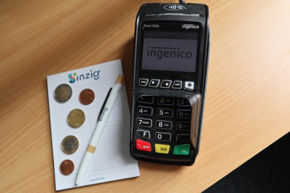 Das Foto zeigt symbolisch ein Kartenlesegerät und etwas Bargeld.