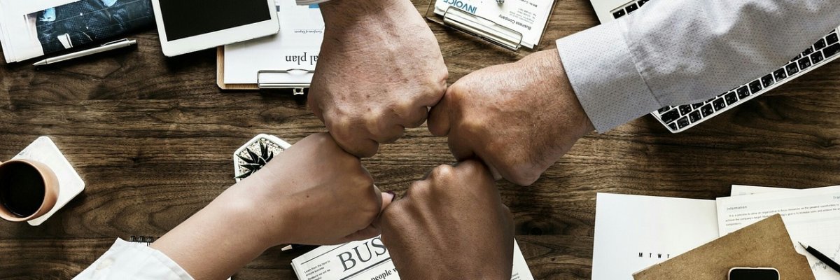 Wirtschaftsförderung Das Bild zeig vier zusammengestreckte Fäuste anlässlich eines erfolgreichen Projektabschlusses